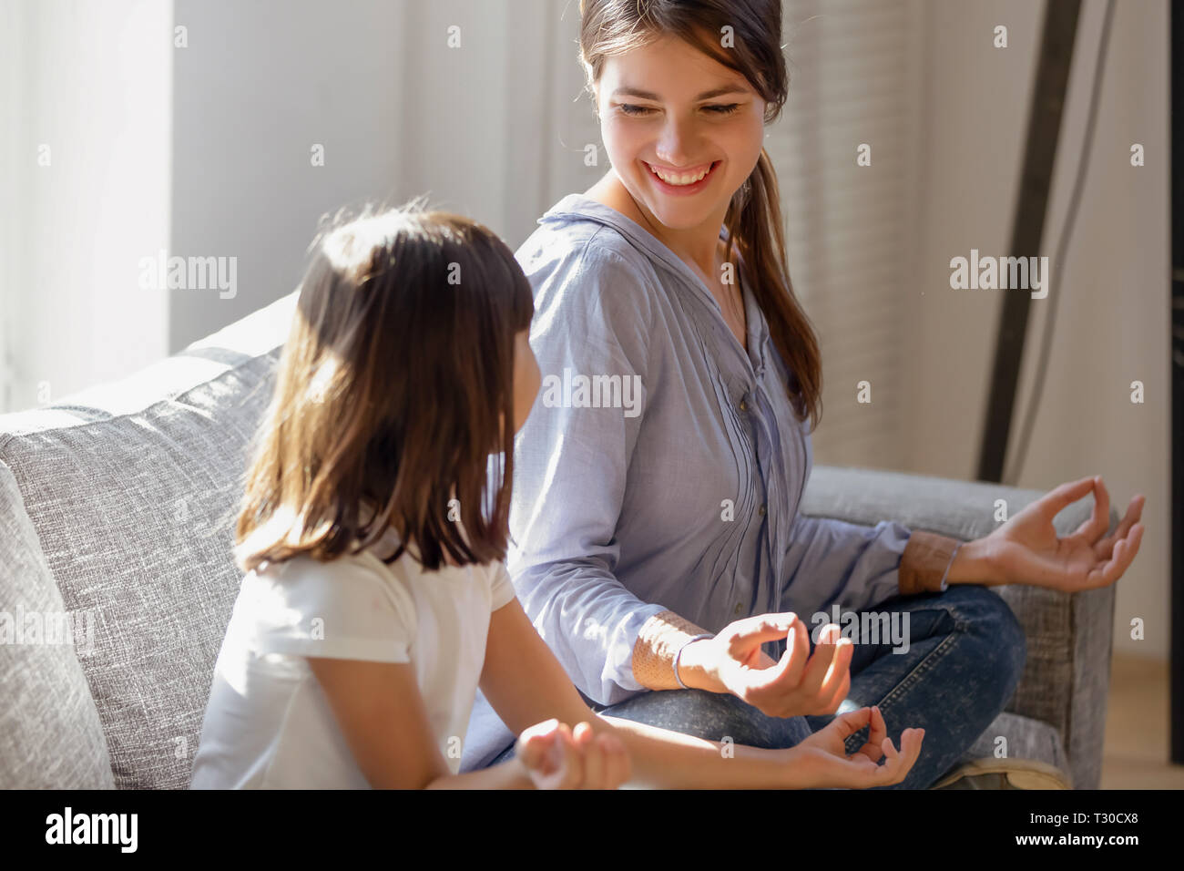 Cheerful mother and daughter sitting in lotus position practice yoga Stock Photo