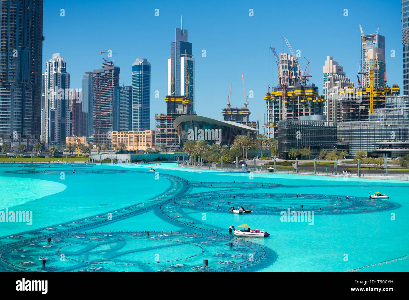 The Dubai fountain lake in the day. boats with workers in diving suits