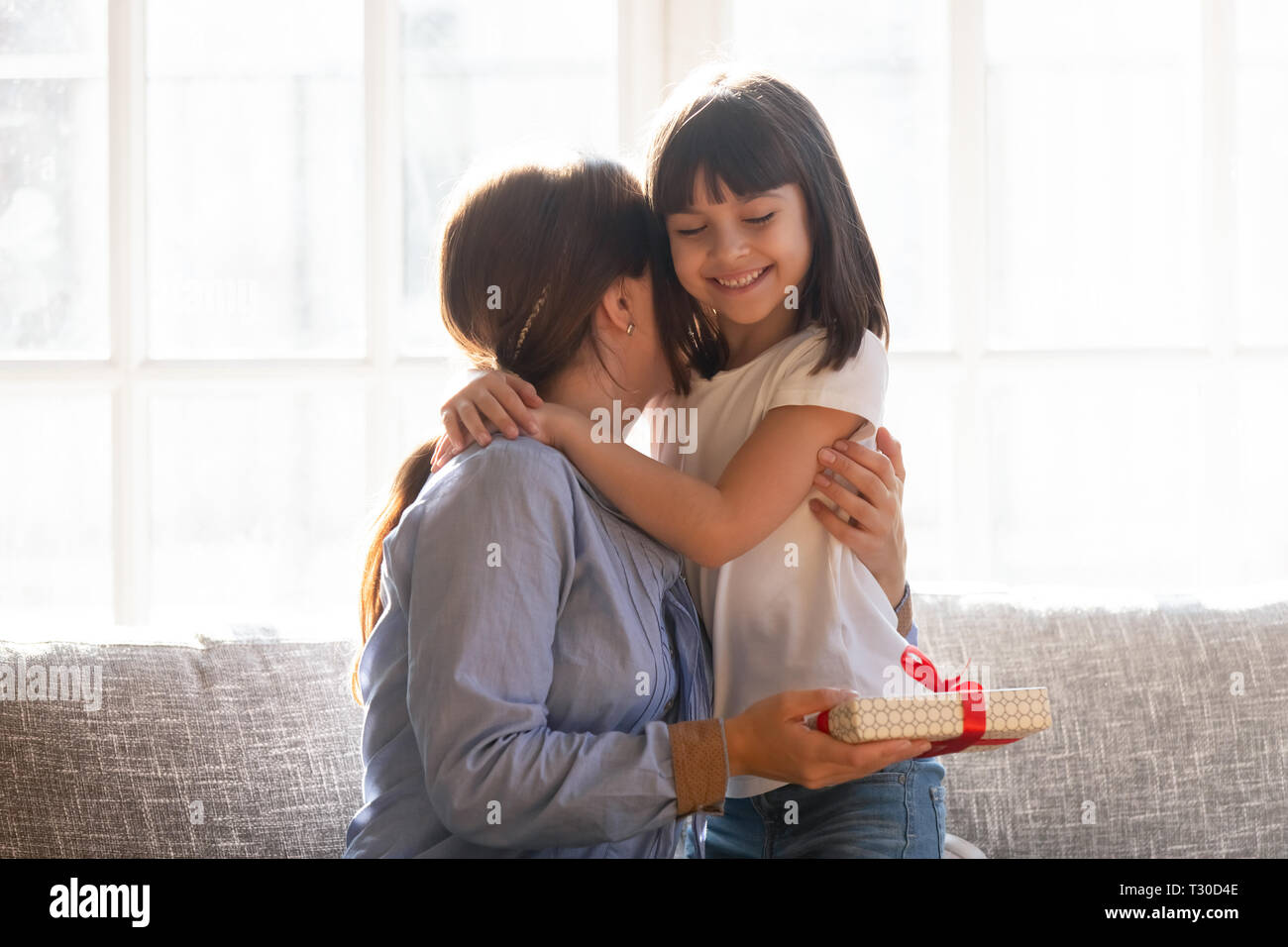 Mother embracing daughter expressing gratitude for received gift Stock Photo