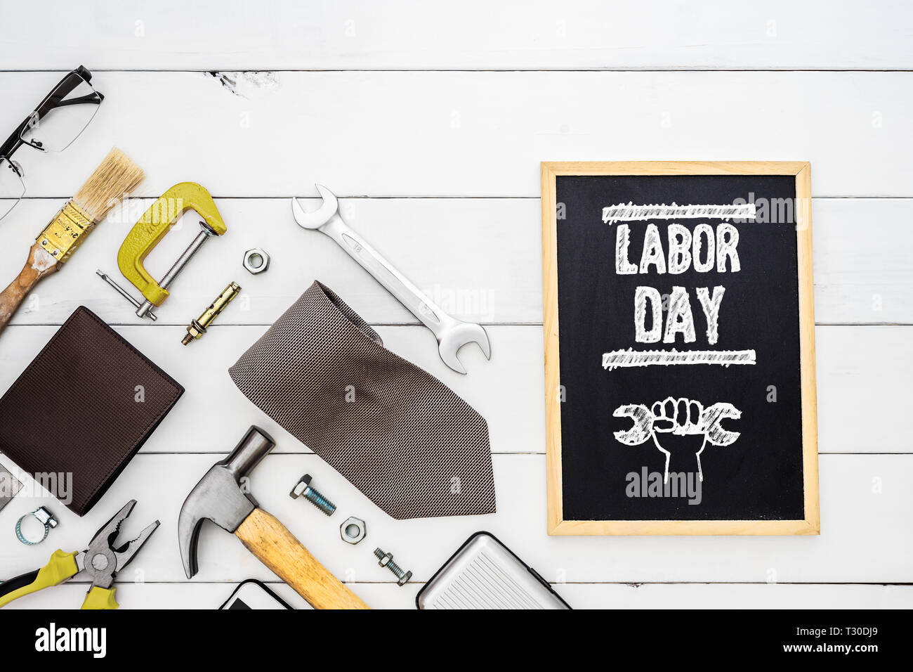 Labor day background concept. Flat lay of construction blue collar handy tools and white collar's accessories over wooden background with black chalkb Stock Photo