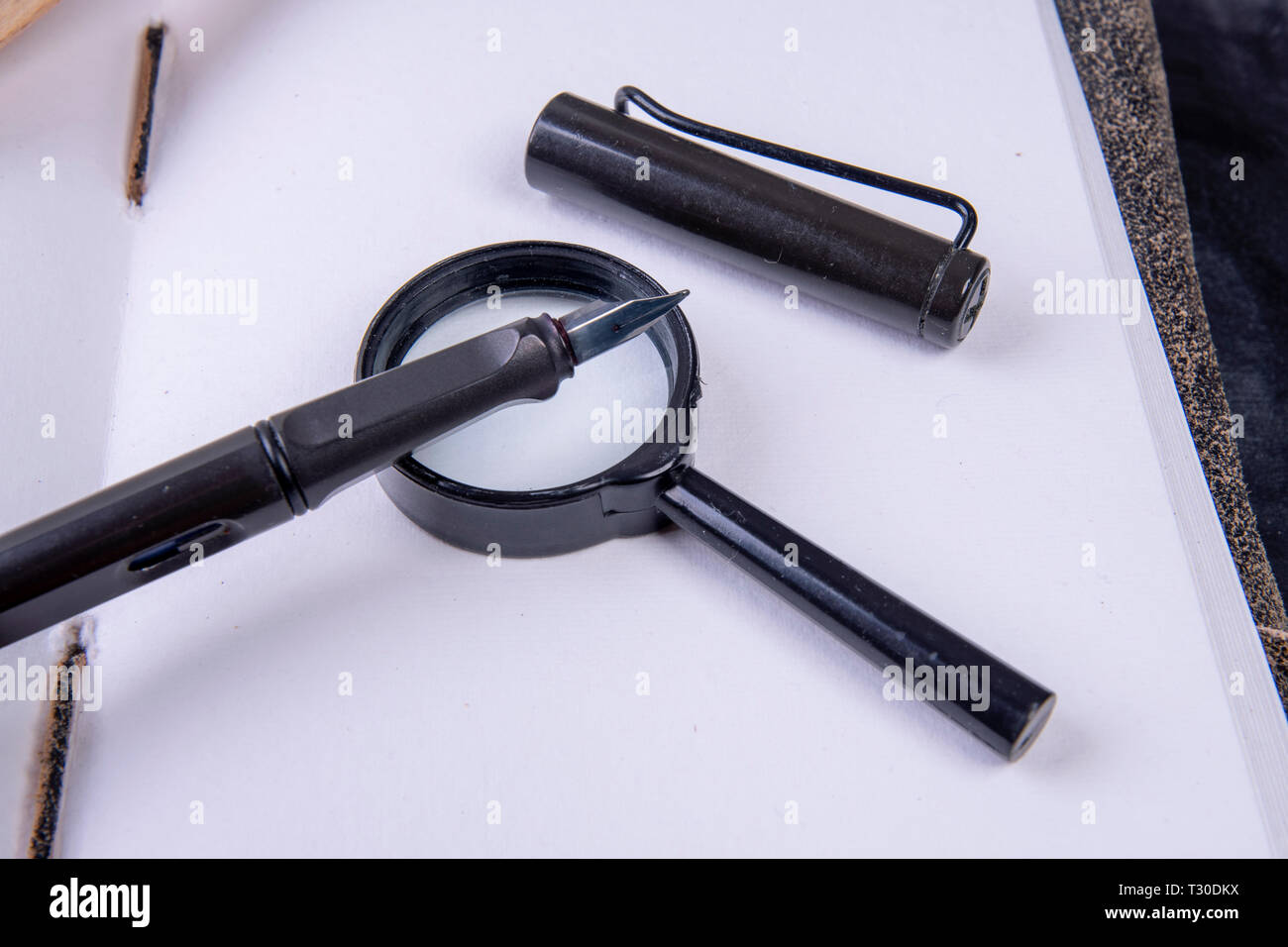 Magnifying glass with fountain pen on an empty notebook Stock Photo - Alamy