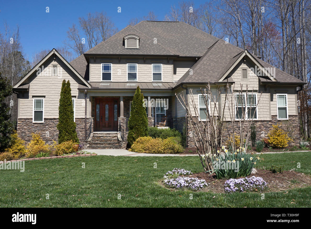 Stone and siding two-story home with flowers in the yard Stock Photo