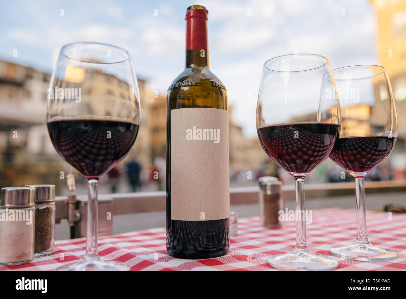 Closeup of bottle red wine and glasses on table of restaurant on background of Piazza della Signoria in summer day Stock Photo