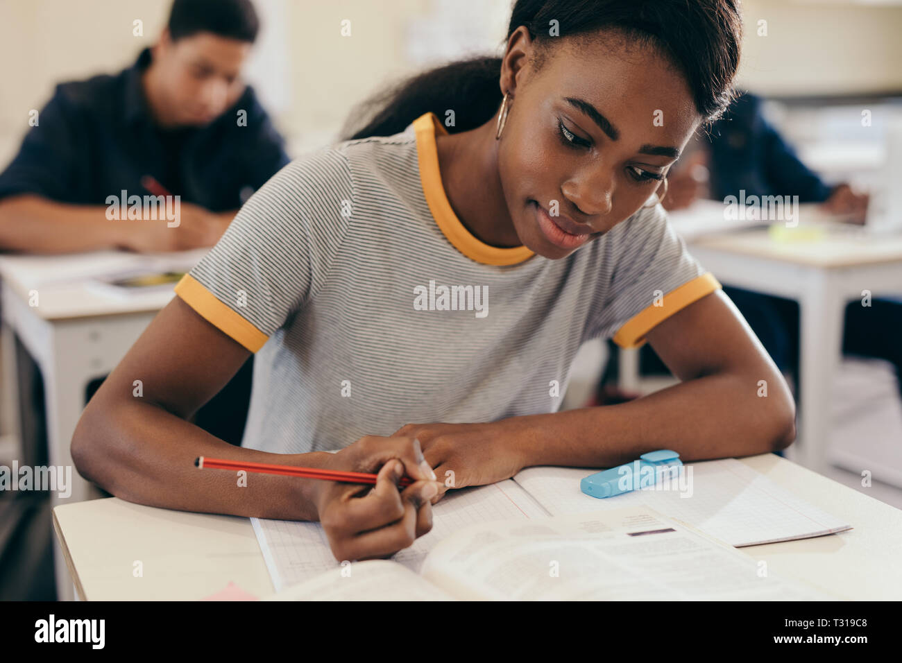 Female student writing notes during a lecture in classroom. Young woman ...