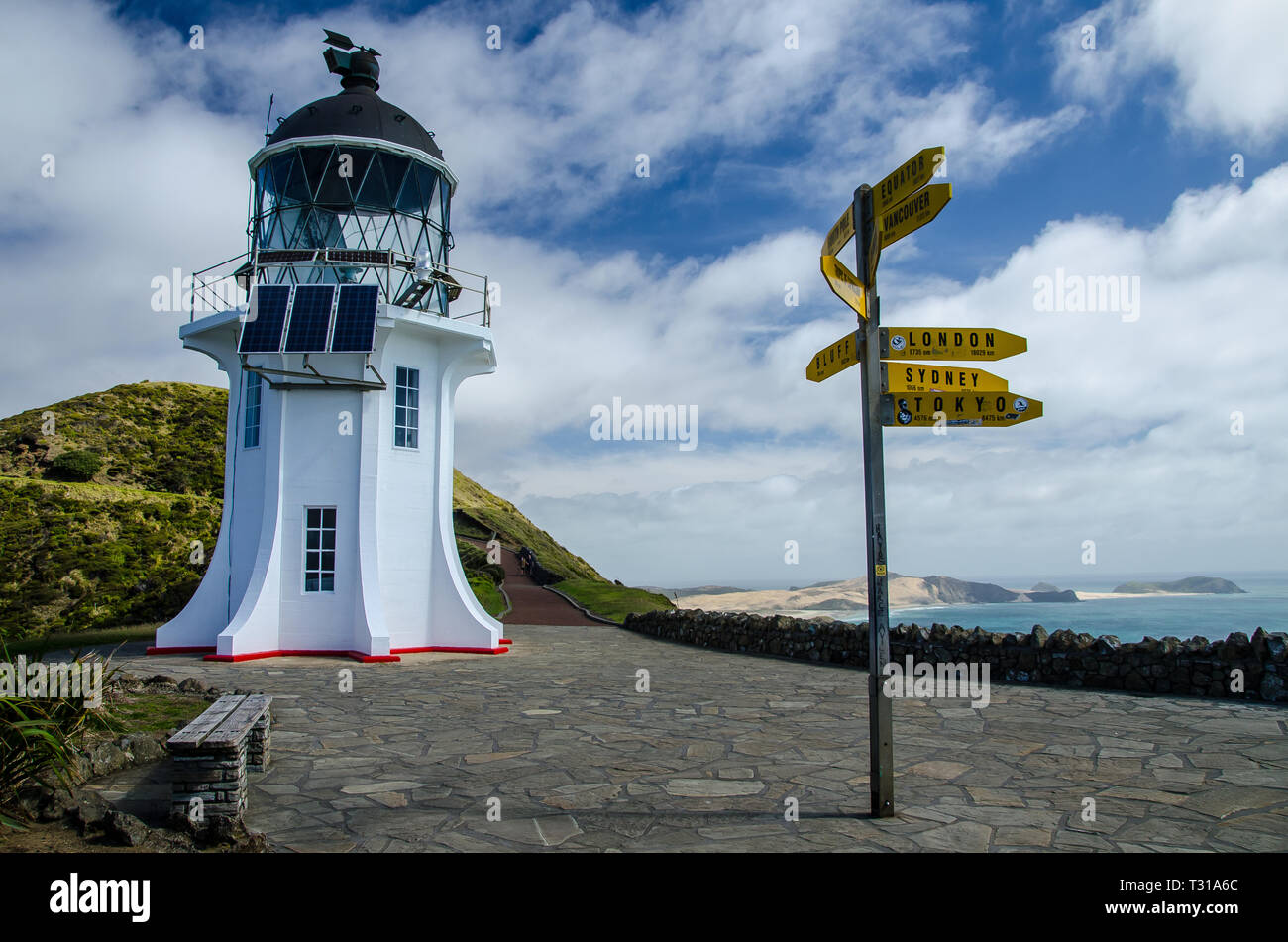 Lighthouse view with signpost from Cape Reinga with blue sky and white clouds above, Northland, New Zealand. Stock Photo