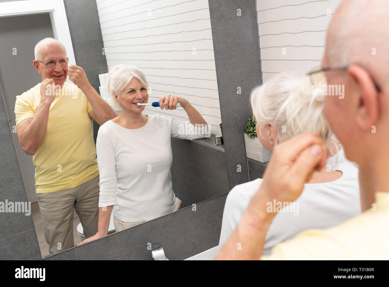 Elderly people using brushing teeth and dental floss. Morning in the bathroom Stock Photo