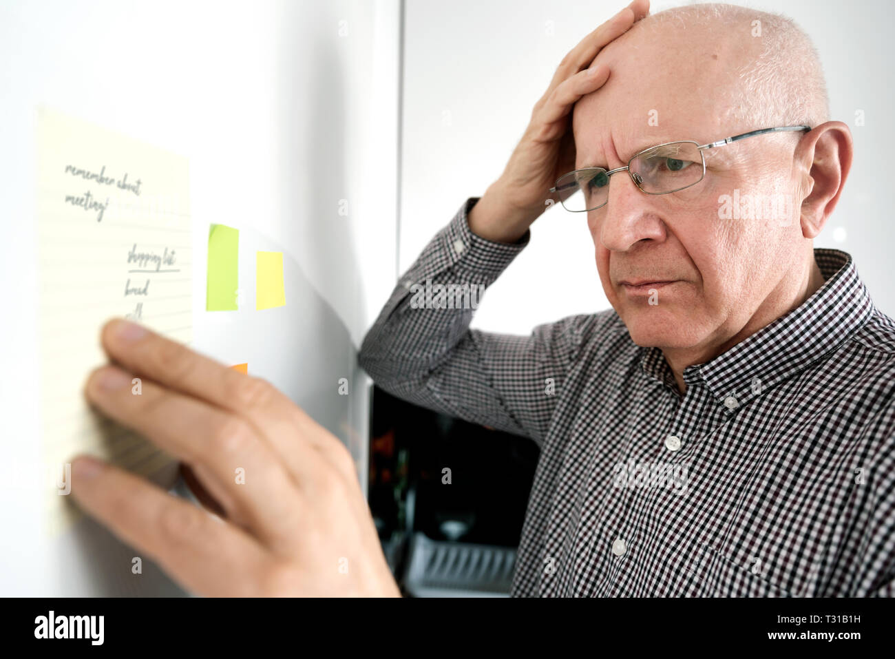 Confused senior man with dementia looking at notes on the fridge Stock Photo