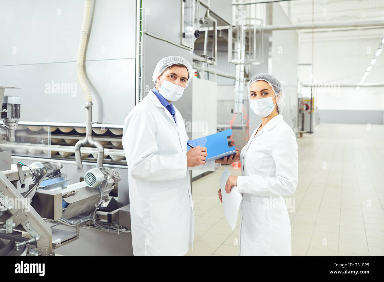 People technologists in masks at food factory. Stock Photo