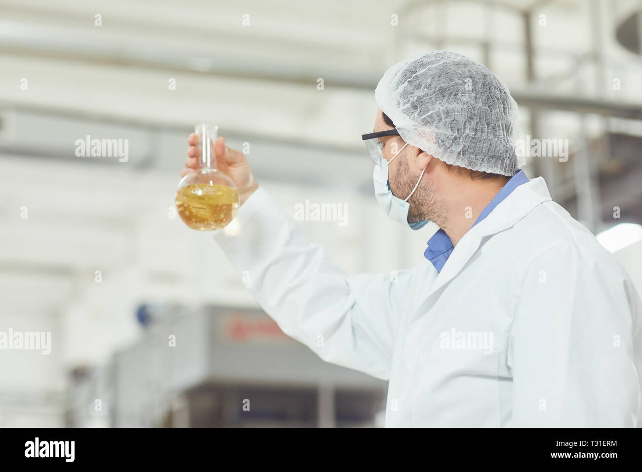 The technologist analyzes the liquid in the flask on the production. Stock Photo