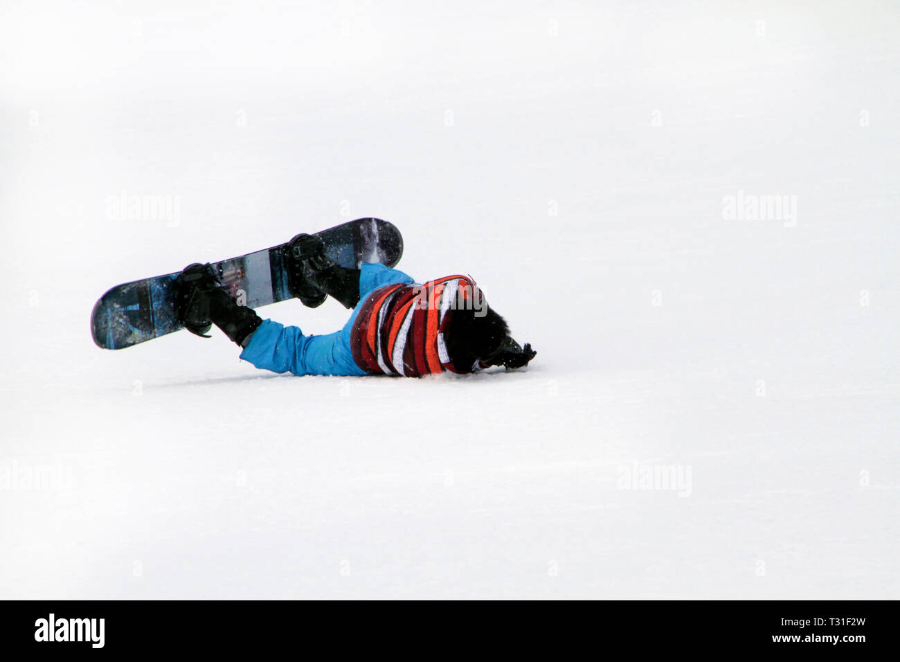 Young man on snowboard falling on his face Stock Photo - Alamy
