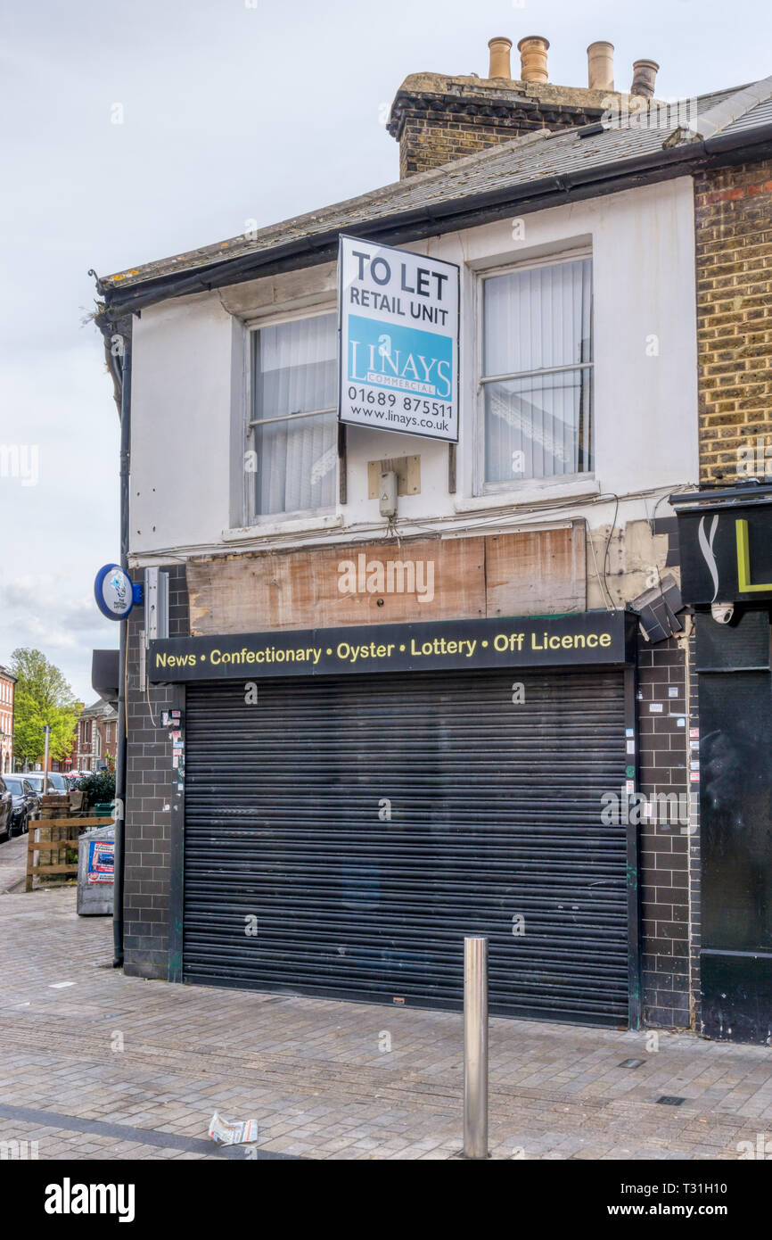 Closed newsagent and corner shop with estate agent's To Let sign. Stock Photo