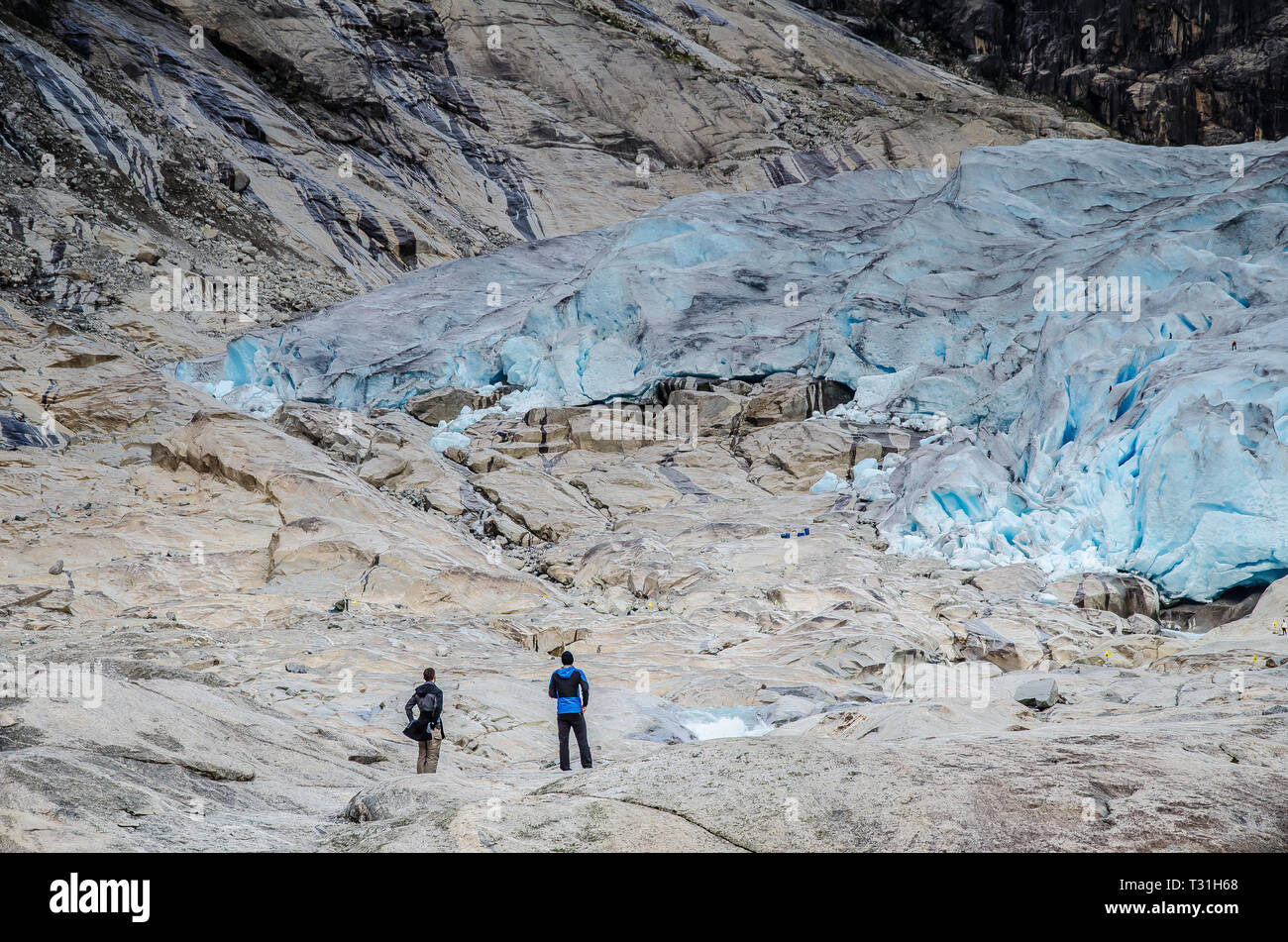 Close view of Nigardsbreen glacier in Jostedal with two tourists looking at the glacier. Stock Photo