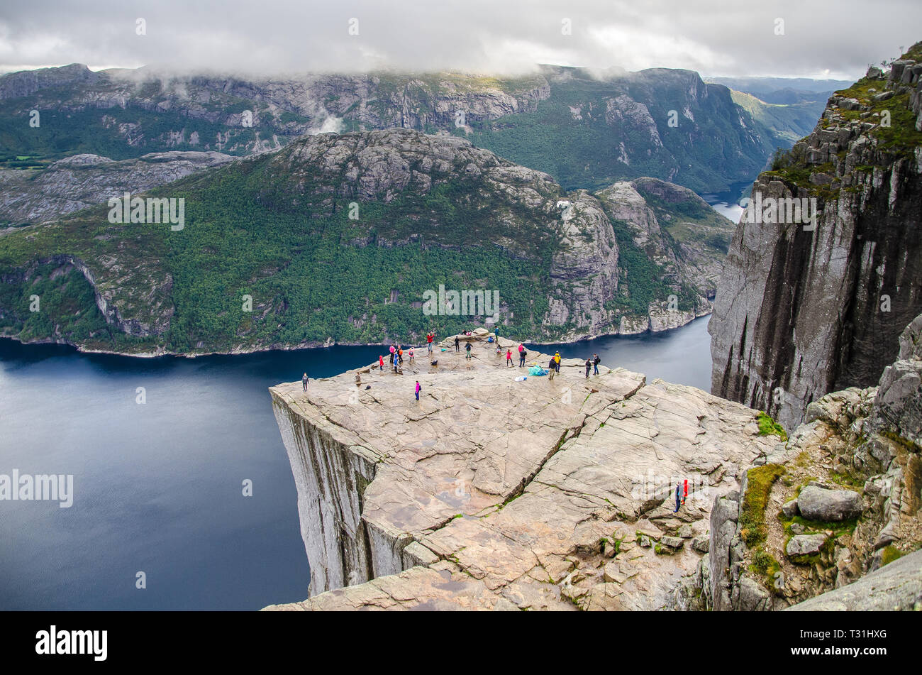 View of people walking on Preikestolen Pulpit Rock from above with a fjord underneath. Stock Photo