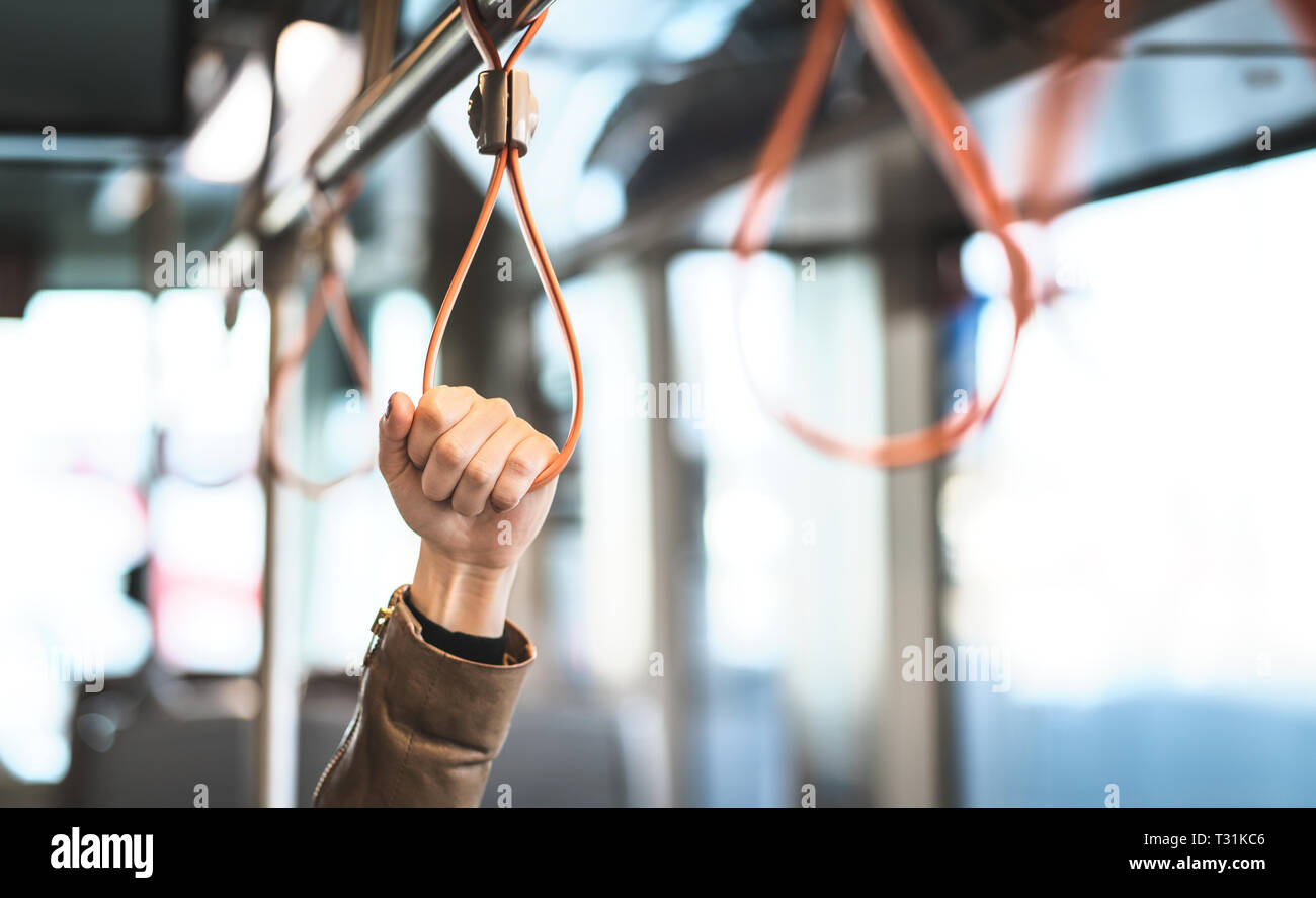 Hand holding the handle in tram, train, bus or subway. Passenger standing in public transportation. Person commuting. Commuter going to work. Stock Photo