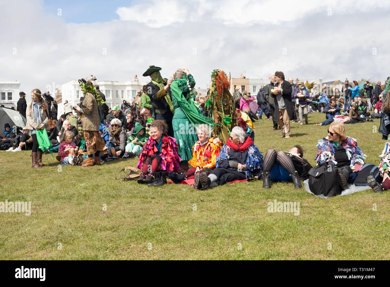 People in costumes sitting on the West Hill waiting for main event to take place on during Jack in the Green festival, Hastings, East Sussex, UK Stock Photo