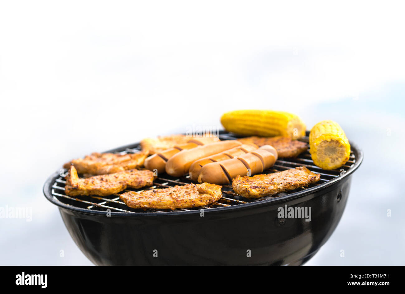 Grill with sausages, meat and corn. Outdoor grilling and barbeque. BBQ party, cookout or camping concept with negative copy space. Stock Photo