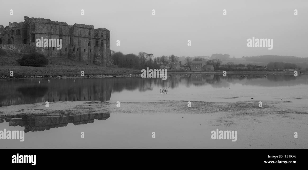 Carew Castle & Mill Reflecting in the water on a misty morning, Pembrokeshire Stock Photo