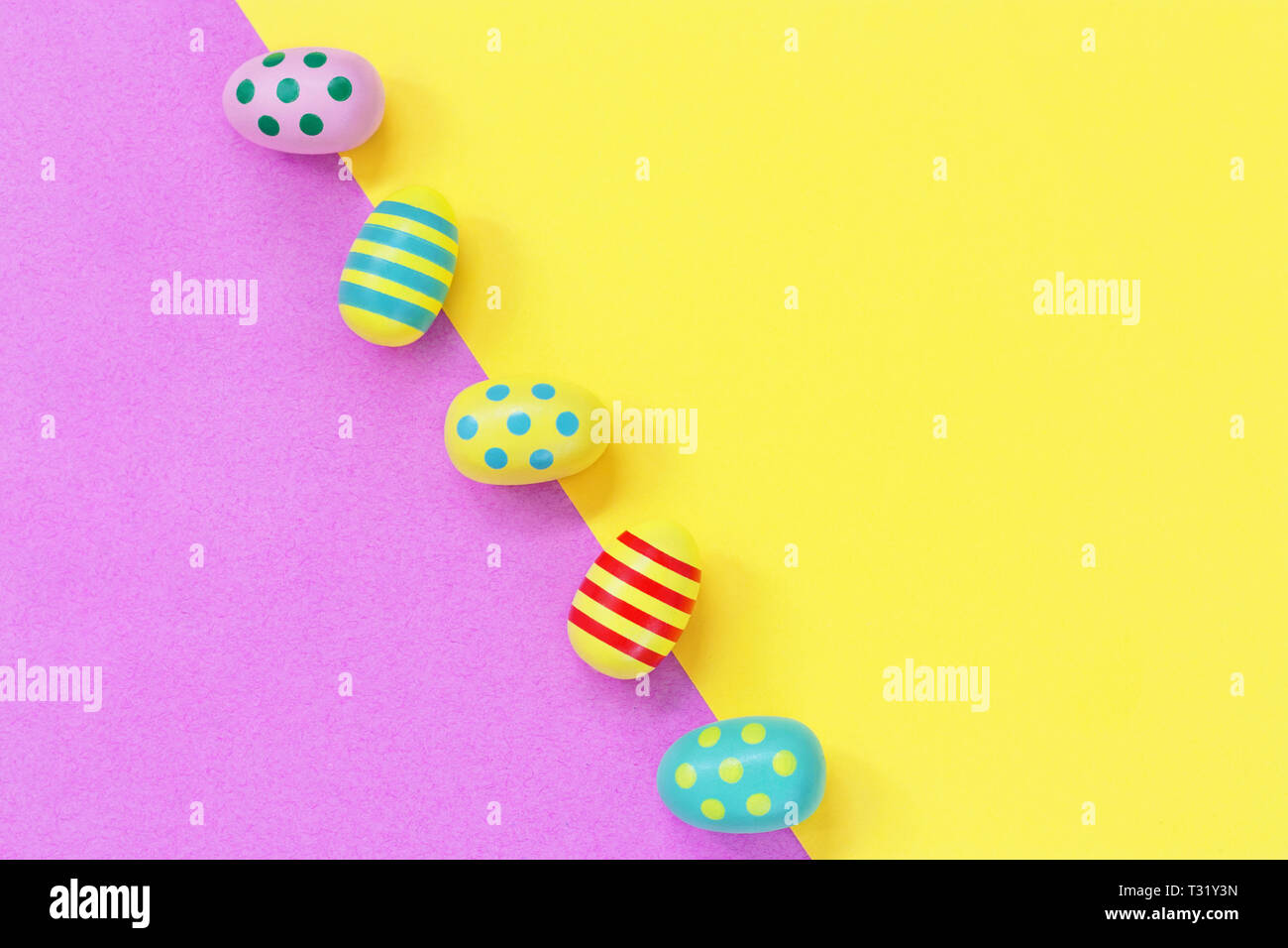 Five colourful Easter eggs on a yellow and pink diagonal background Stock Photo