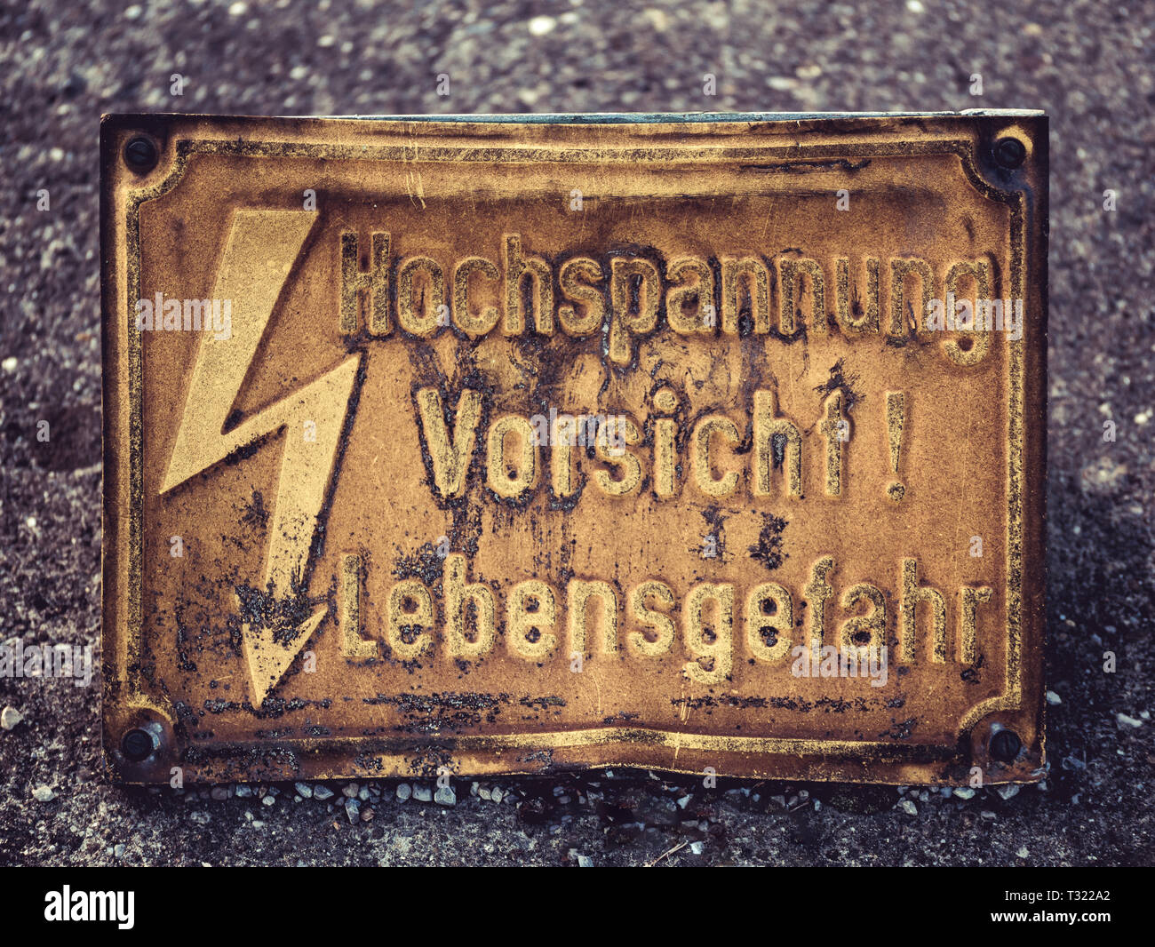 Image of an old yeloow warning sign with flash and german words Hochspannung Vorsicht Lebensgefahr, which means Danger High Voltage Stock Photo