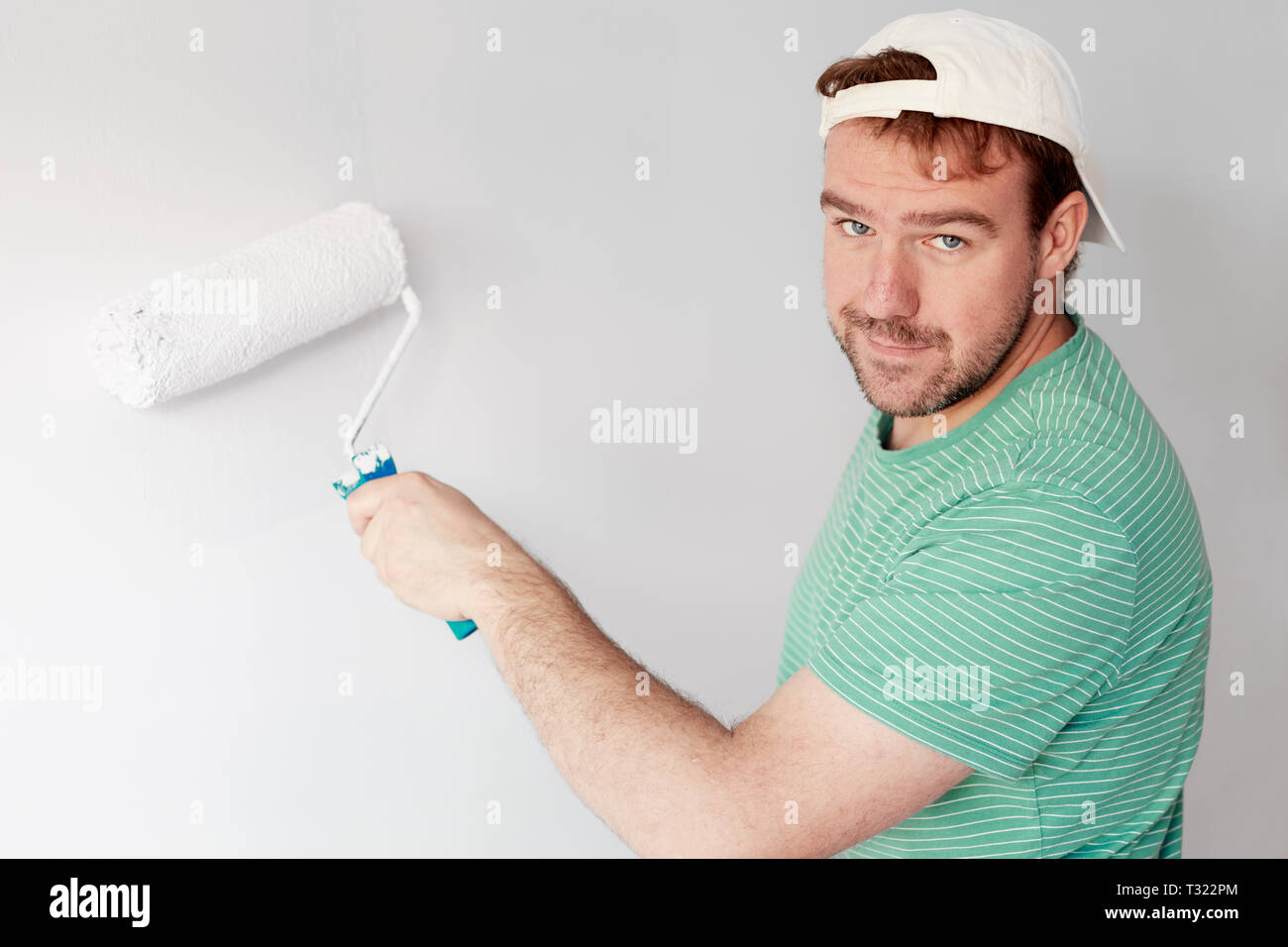 Young man painting a wall on white in a modern home Stock Photo