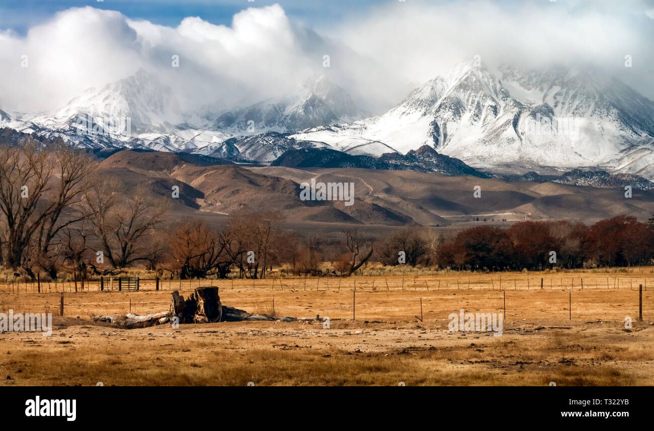 storm clouds clearing after snowfall in the eastern Sierra Nevada mountains in California farmland in the foreground Stock Photo