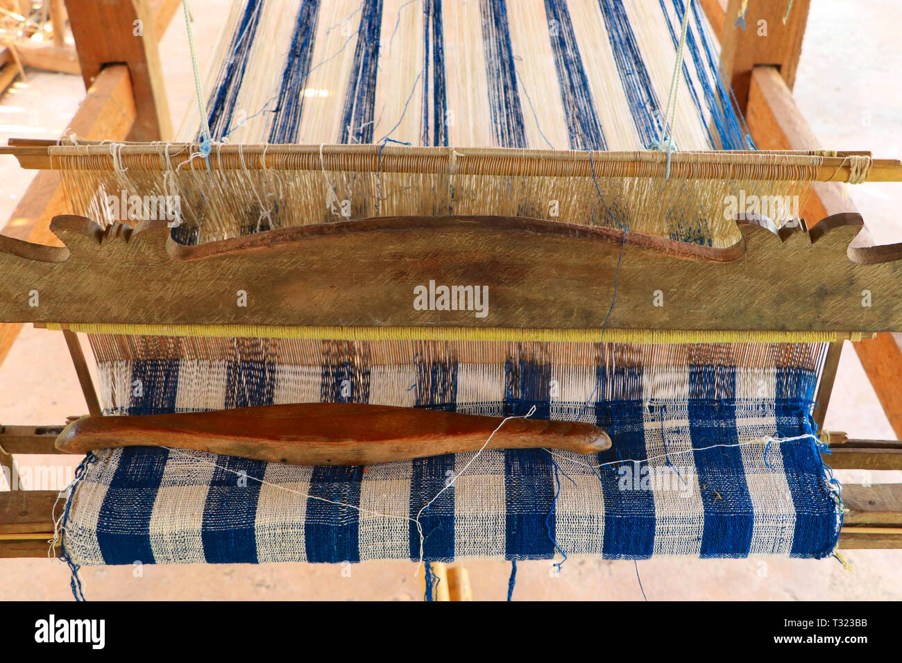 Wooden weaving loom with colorful pattern textile and weaving shuttle