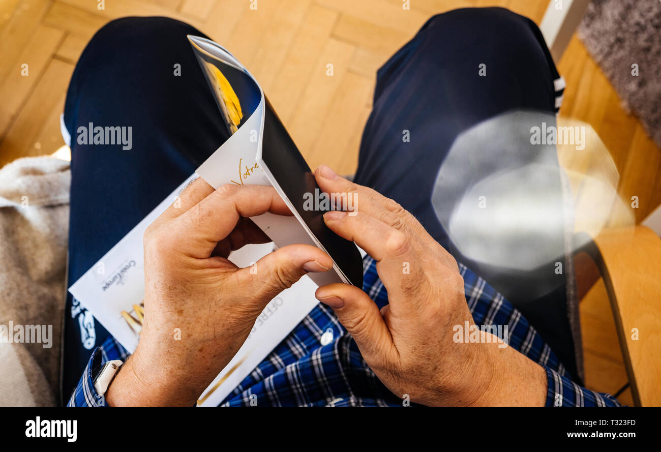Paris, France - Mar 30, 2019: View from above of senior man opening new advertising leaflet from CroisiEurope Alsace Croisieres until 1997 an international river cruise company Stock Photo