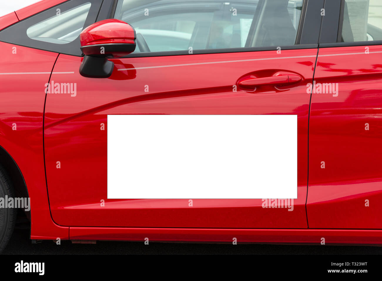 Horizontal shot of a blank white magnetic sign on a red car’s driver side door. Stock Photo