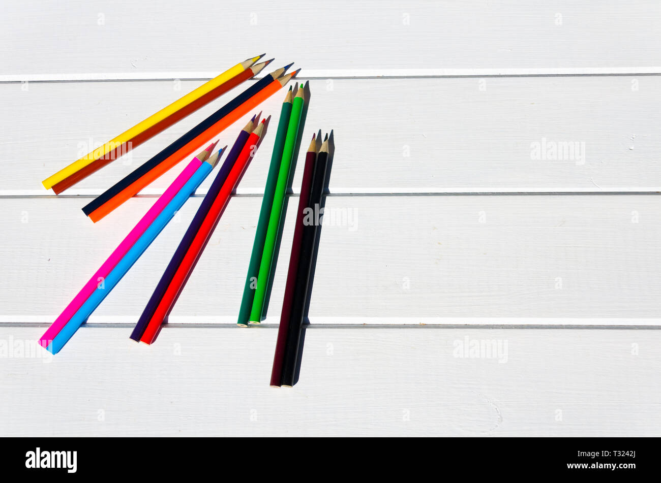 Colored pencils aligned on white pallet table Stock Photo