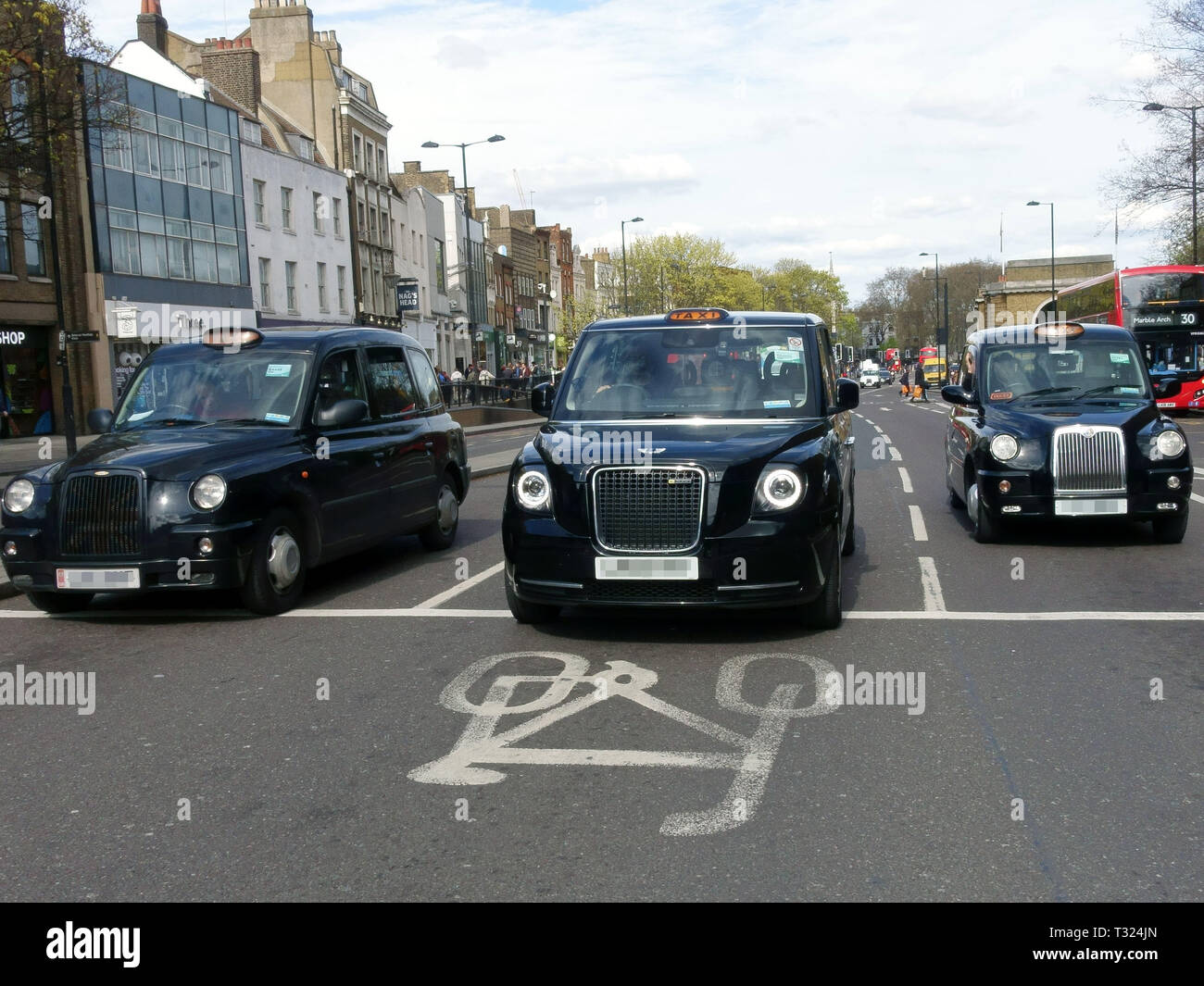 TX electric London taxi by London Electric Vehicle Company (LEVC) flanked by two older diesel taxis Stock Photo
