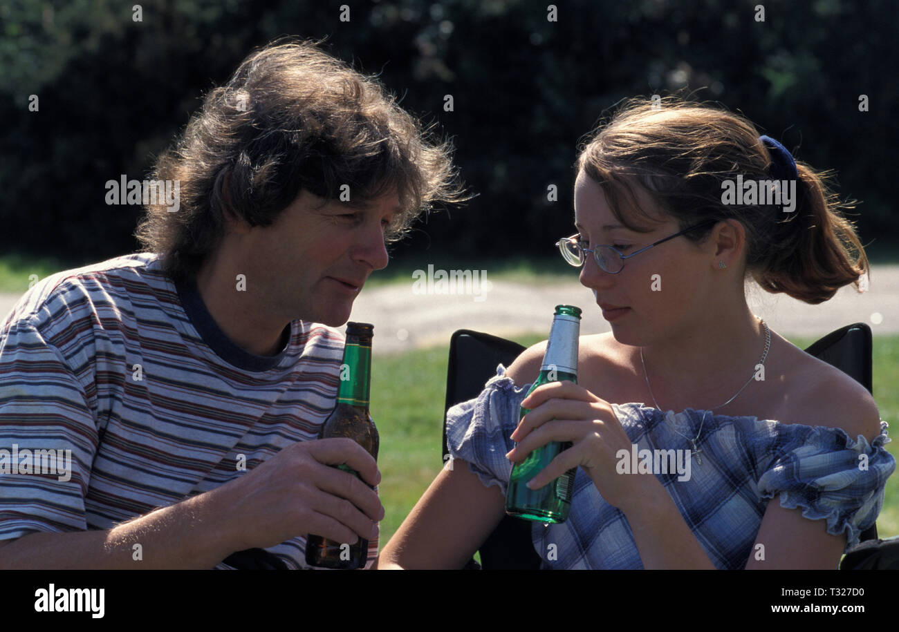 father and teenage daughter drinking bottle of beer Stock Photo