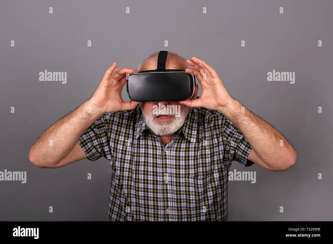 Man wearing virtual reality goggles. Studio shot, gray background Stock Photo
