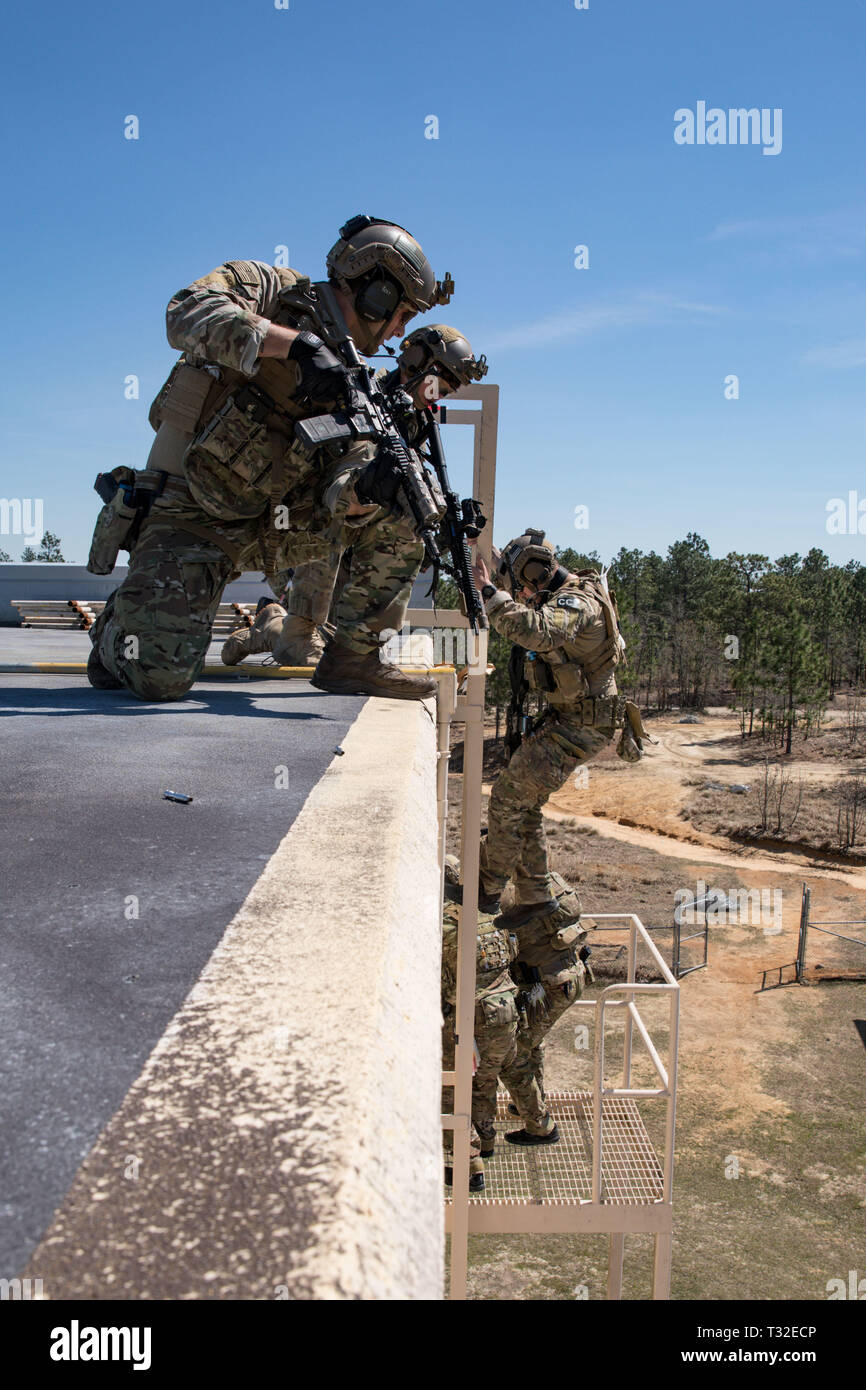 Green Berets assigned to 3rd Special Forces Group (Airborne) pull security while they exit a rooftop to clear the building during a routine training exercise, April 3, 2019 at Fort Bragg, NC. Green Berets utilized the Special Patrol Insertion/Extraction System, or SPIES, to insert themselves on the rooftop. (U.S. Army photo by Sgt. Steven Lewis) Stock Photo