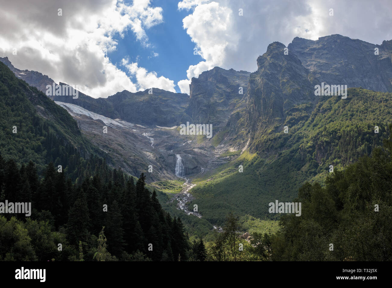 Closeup view mountains scenes and far away waterfall in national park Dombai, Caucasus, Russia, Europe. Summer landscape, sunshine weather and sunny d Stock Photo