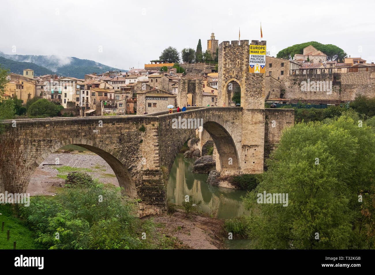 The Fluvià river flows under the arches of the medieval bridge of Besalu, Catalonia adorned with a banner calling for the release of Catalan political Stock Photo