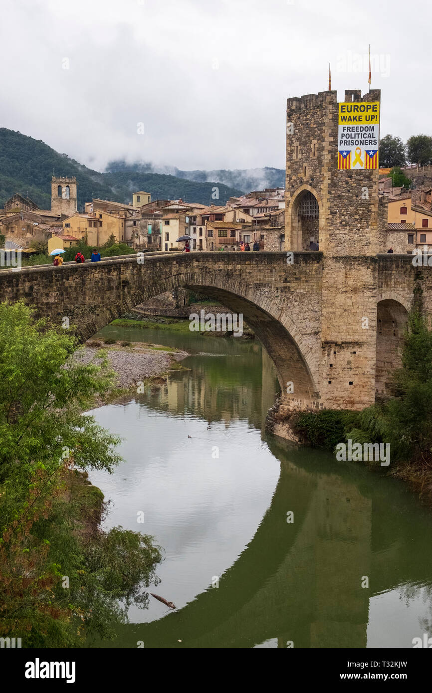 The Fluvià river flows under the arches of the medieval bridge of Besalu, Catalonia adorned with a banner calling for the release of Catalan political Stock Photo
