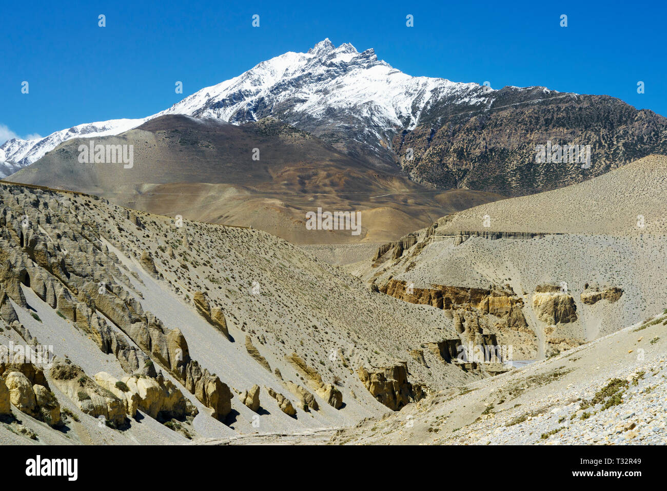 Desertic scenery and snow capped mountain between Tangbe and Chuksang, Upper Mustang region, Nepal Stock Photo