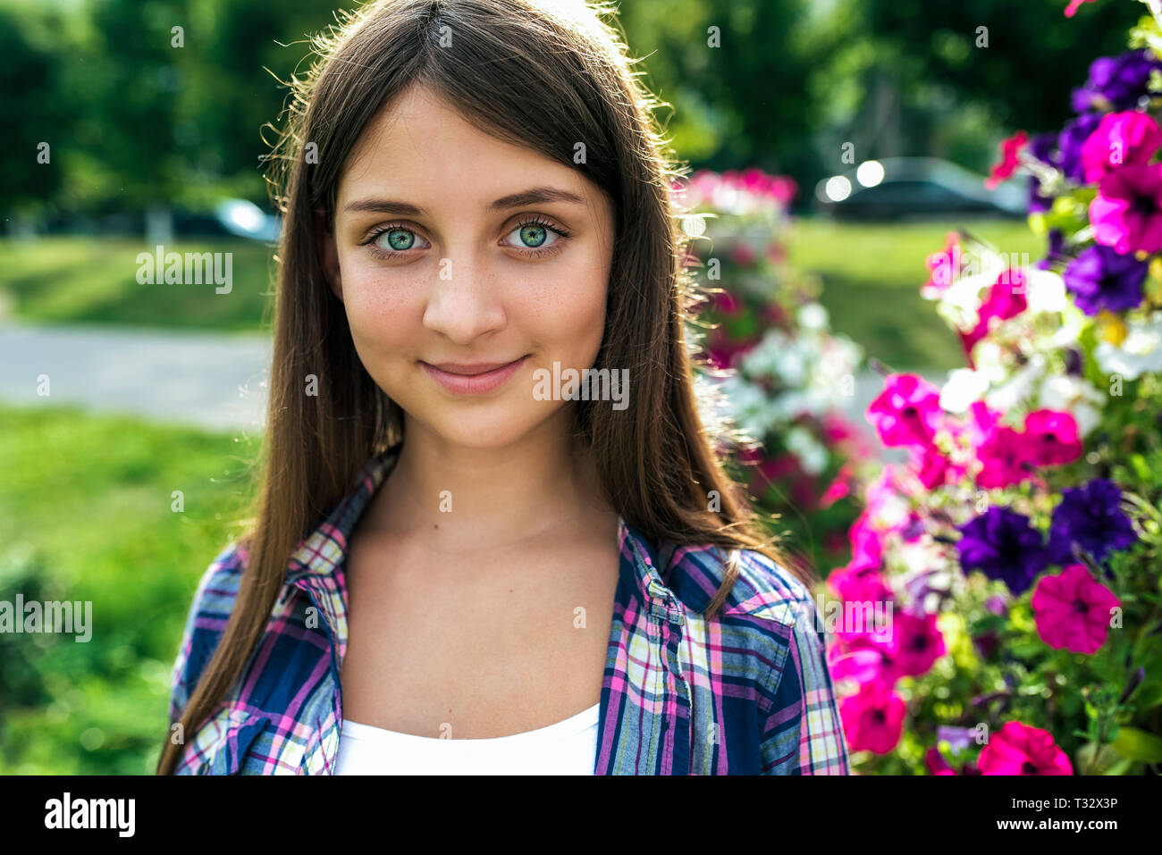 Beautiful girl schoolgirl 1215 years old, stands in the summer against the background of