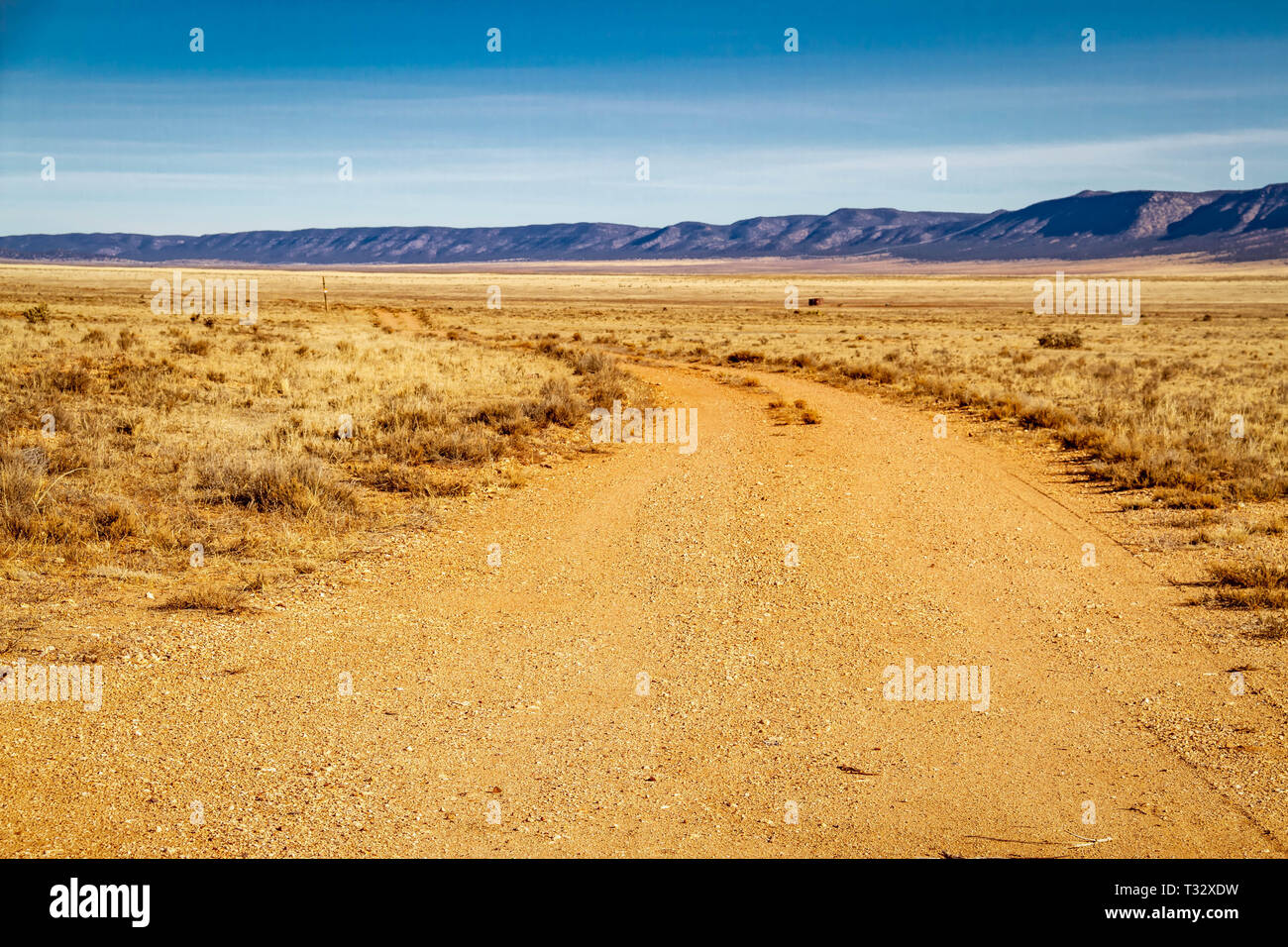 A dirt road in the desert that curves as it moves away from the viewer. Stock Photo