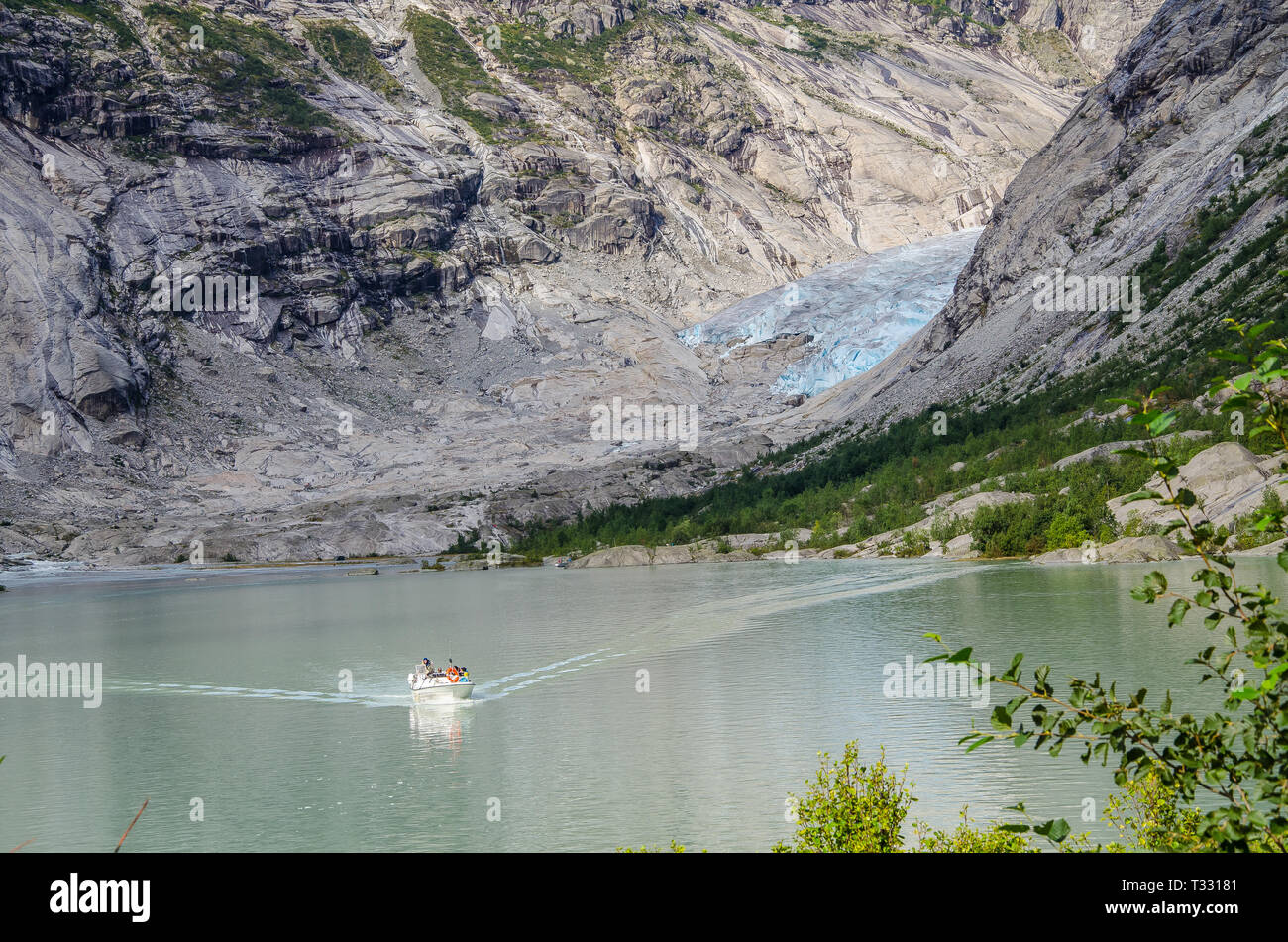 Distance view of the Nigardsbreen glacier with boat on the lake in the foreground. Stock Photo