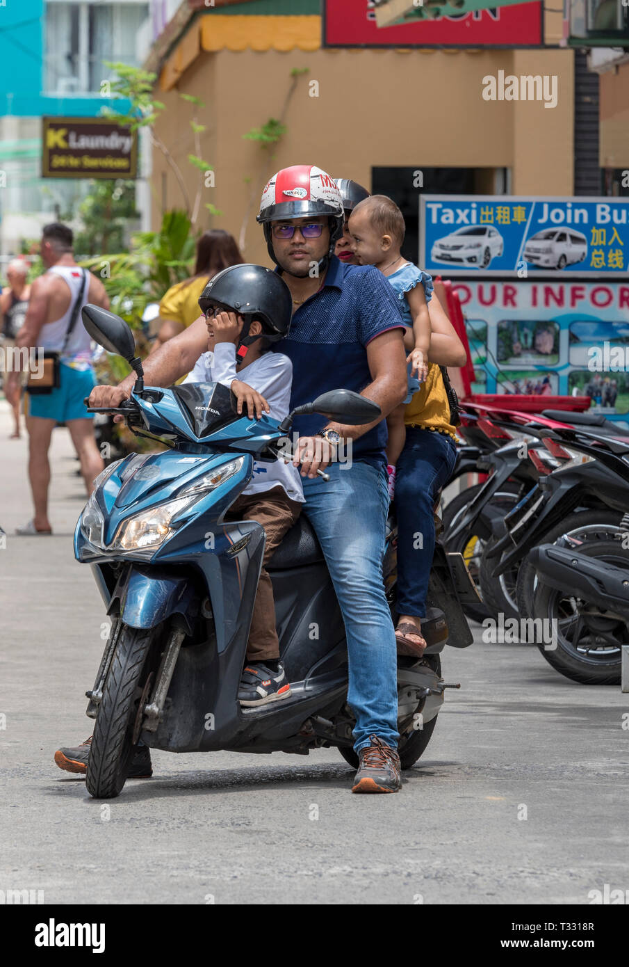 a motorcycle or scooter rider in thailand carrying his whole family
