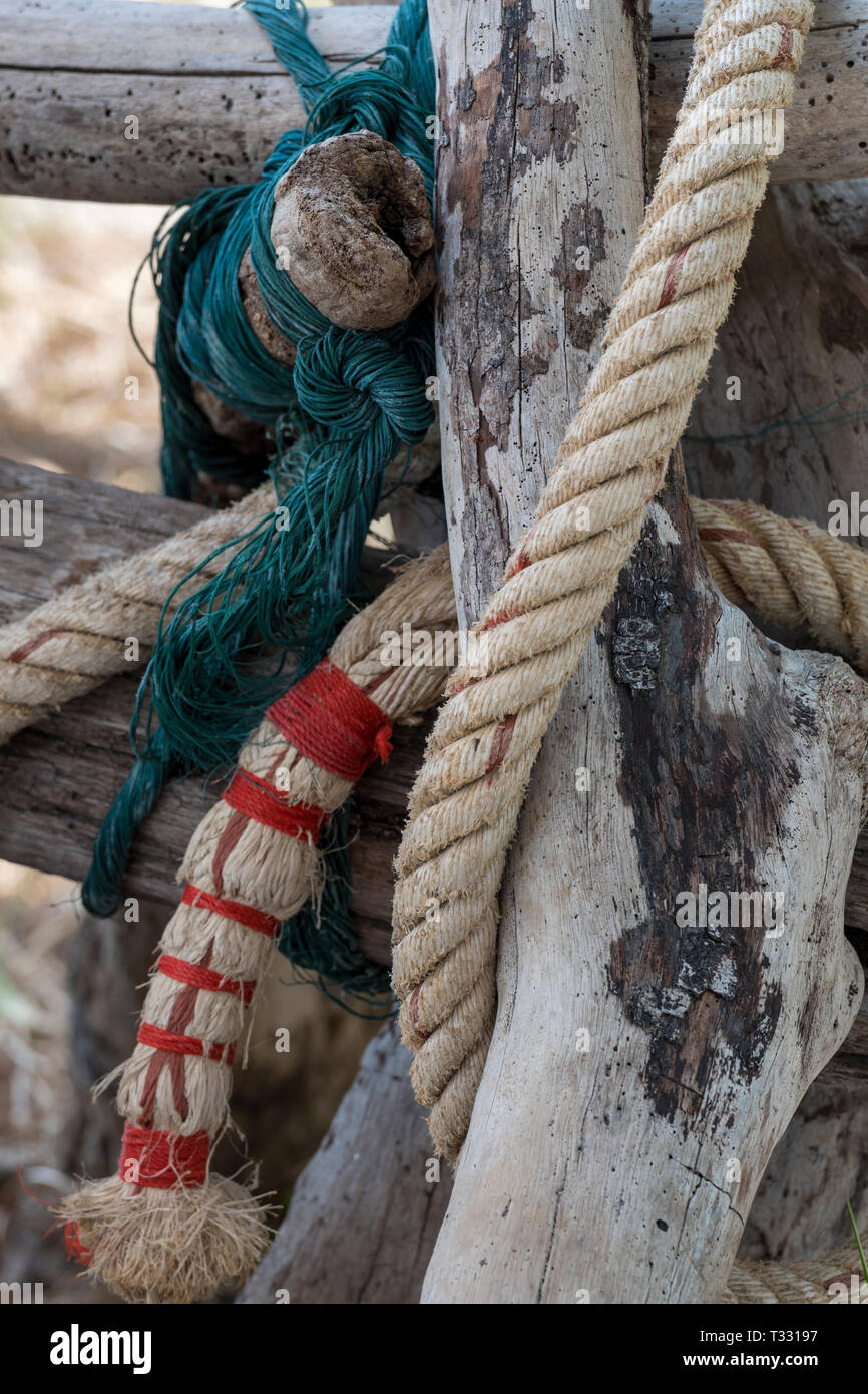 Old ropes, wires and driftwood flotsam and jetsam on the shoreline at the seaside in a maritime nautical marine theme background. Stock Photo