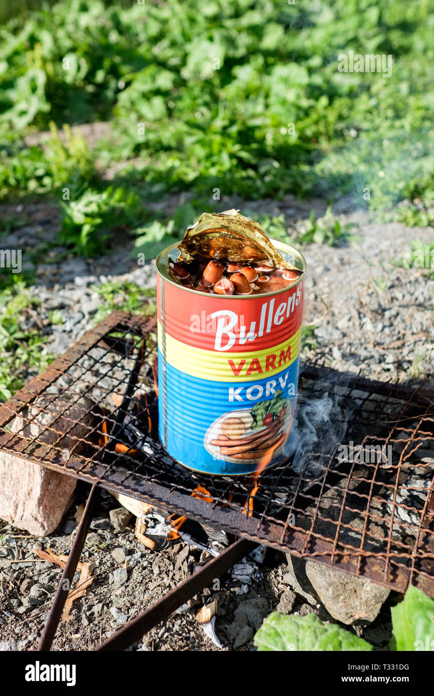Cooking a tin of Bullens hotdogs on a barbecue outdoors in Sweden in summer. Stock Photo