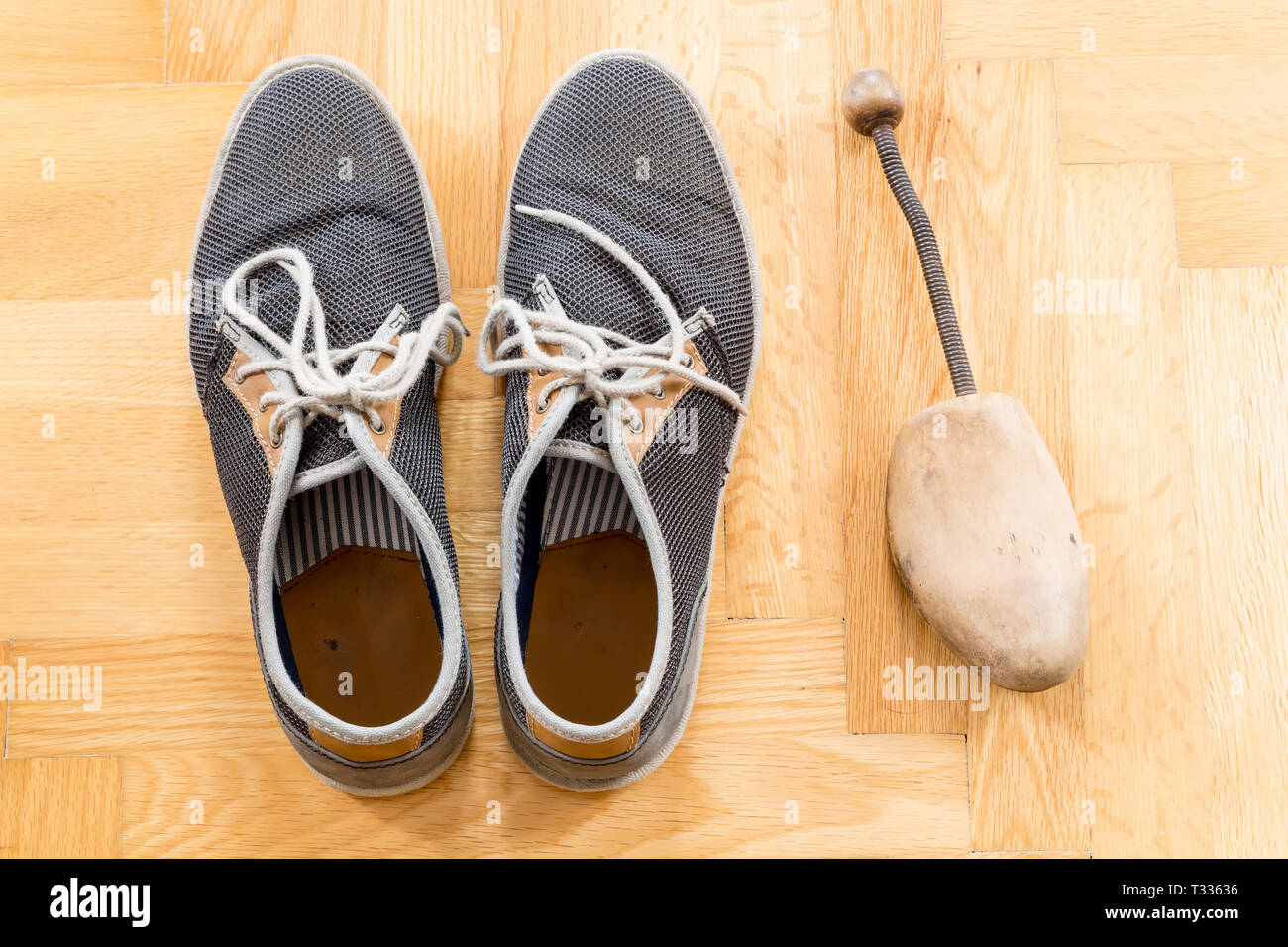 A pair of used sneakers with shoe stretcher on the floor Stock Photo - Alamy