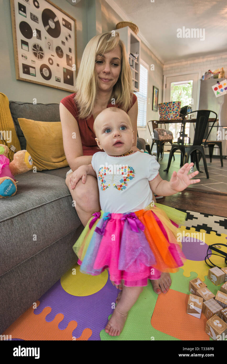 One year old girl learning to walk, her mother looks on Stock Photo