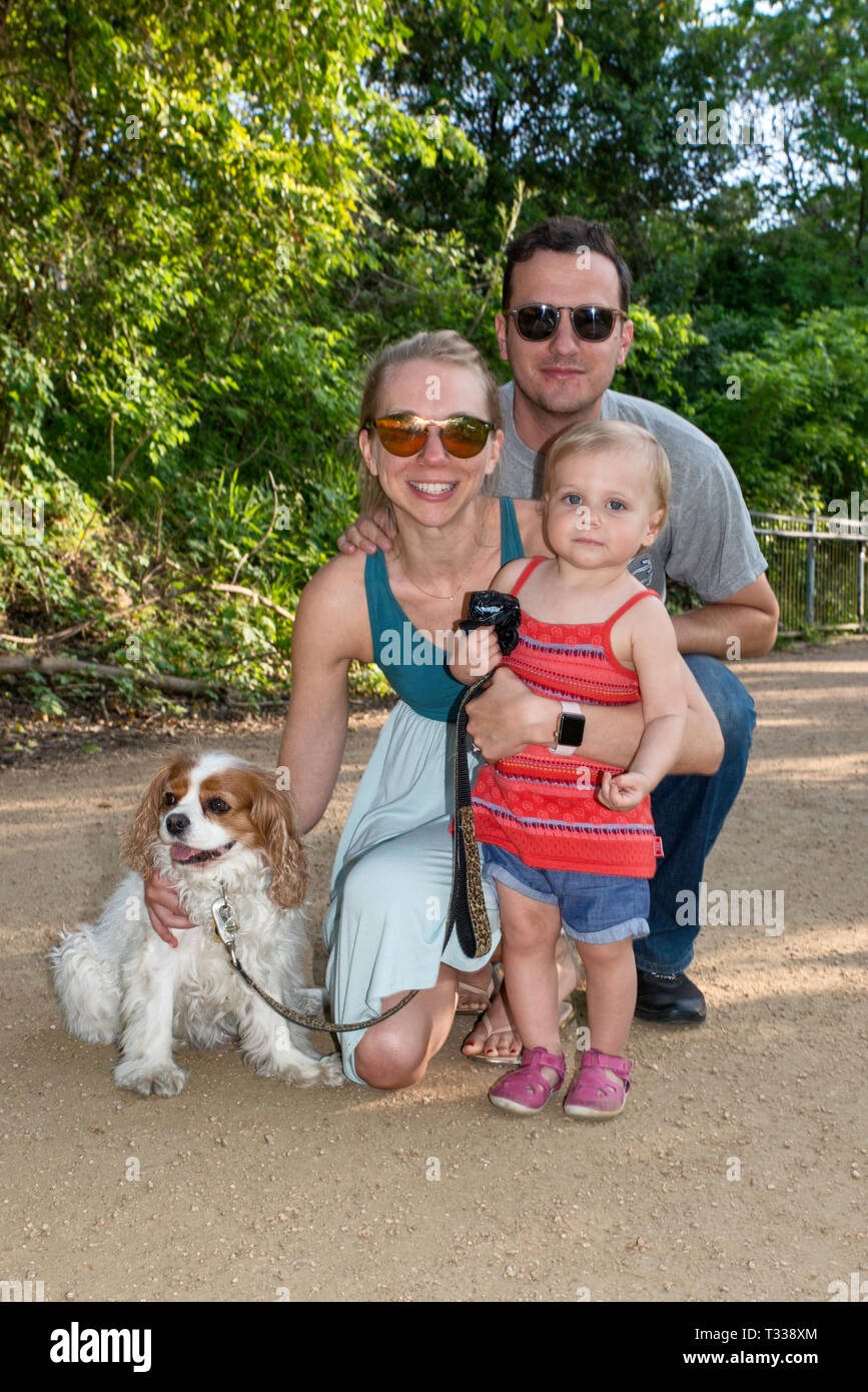 Father, mother, girl toddler and Cavalier King Charles Spaniel, at Butler Trail in Zilker Park in Austin, Texas, USA Stock Photo