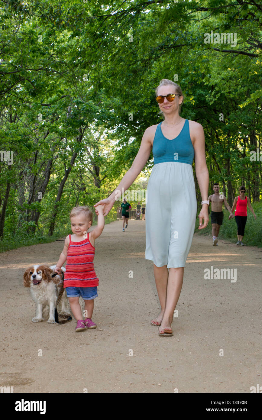 Mother, girl toddler and Cavalier King Charles Spaniel, at Butler Trail in Zilker Park in Austin, Texas, USA Stock Photo