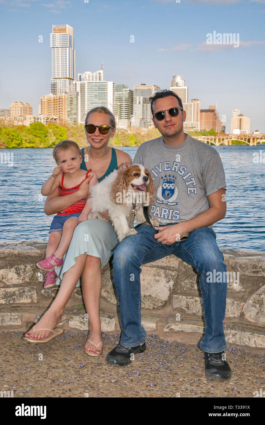 Father, mother, girl toddler and dog, at Lou Neff Point over Lady Bird Lake, downtown towers in distance, Zilker Park in Austin, Texas, USA Stock Photo