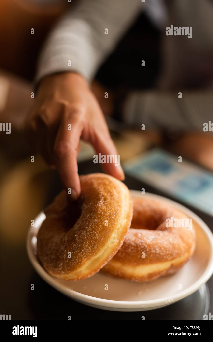 take a donut by woman's hand in house Stock Photo