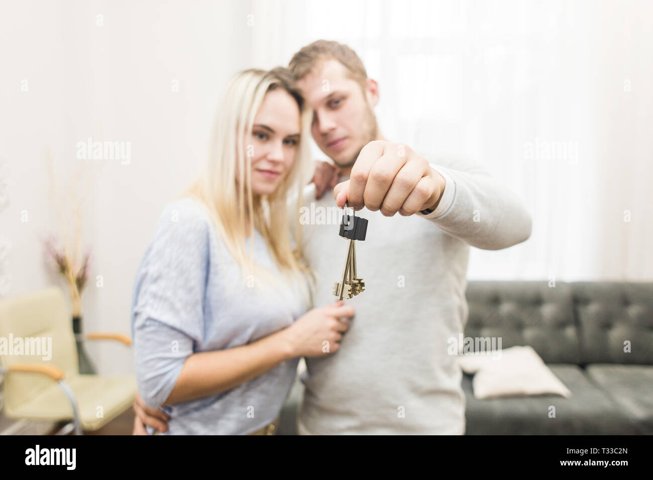 A lovely young couple holds in front of them the keys to their new ...